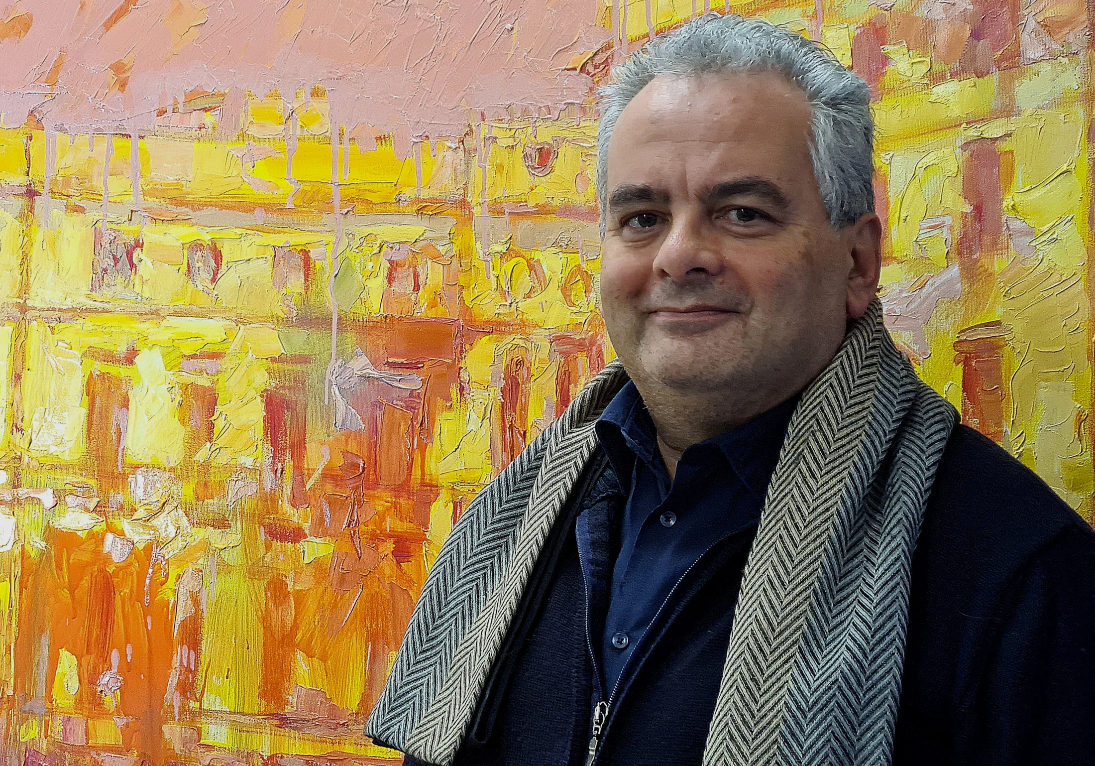 Domenico Asmone davanti a un dipinto dai toni gialli e arancio